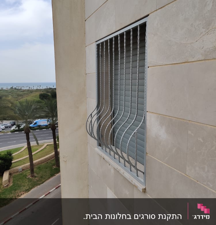 סורגי מתכת על חלון בניין עם תריסים סגורים